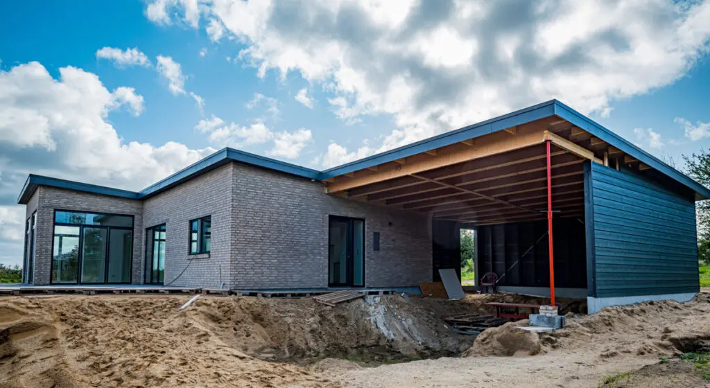 Nyopført tilbygning og carport med rå murstensfacade og integreret overdækning under opførelse