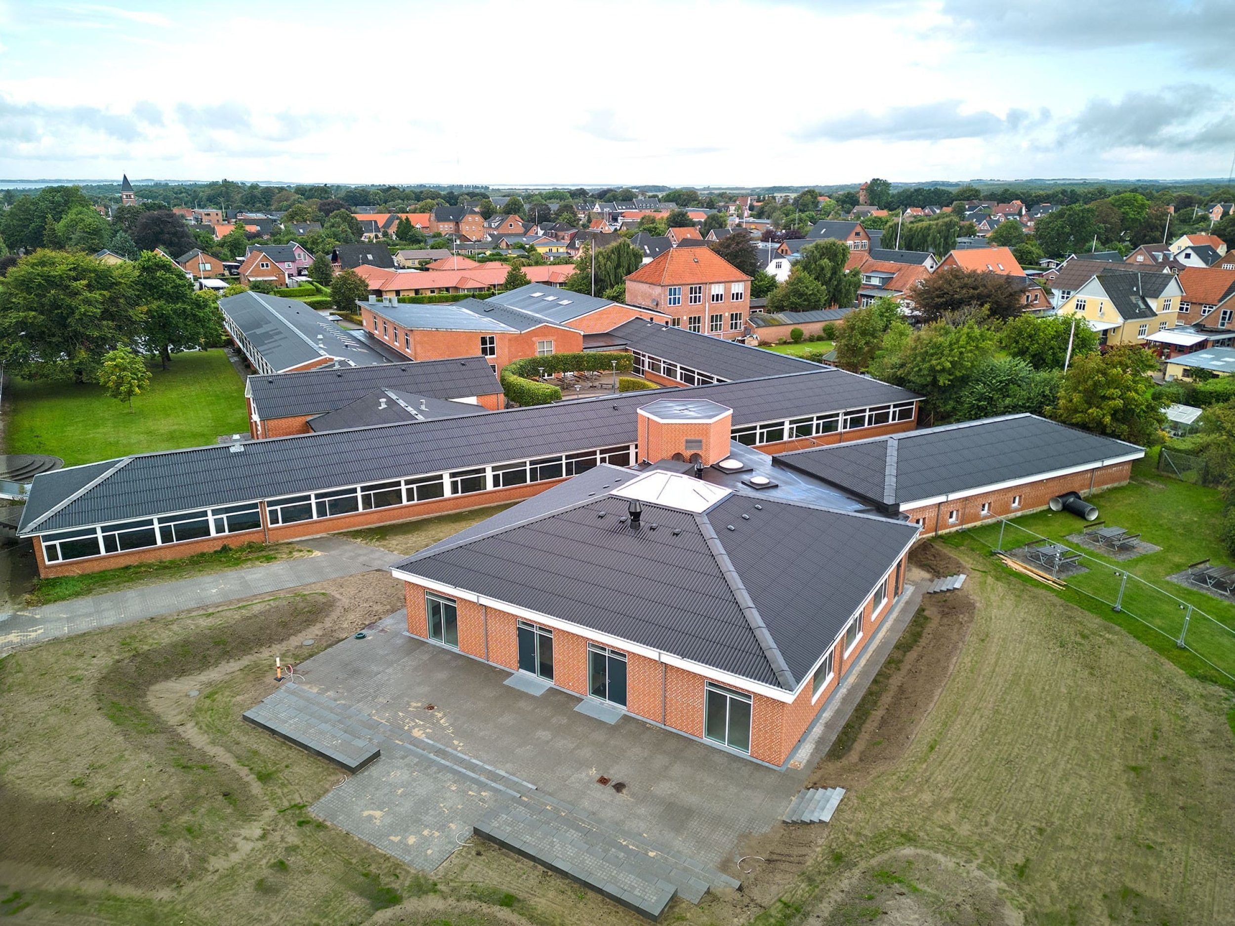 Luftfoto af færdigt skolebyggeri i røde mursten med flisebelægning ved Vinderup Realskole
